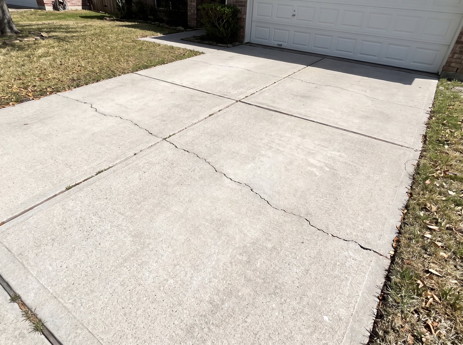 The same driveway after one afternoon of pressure washing: clean, even concrete from the garage to the street.
