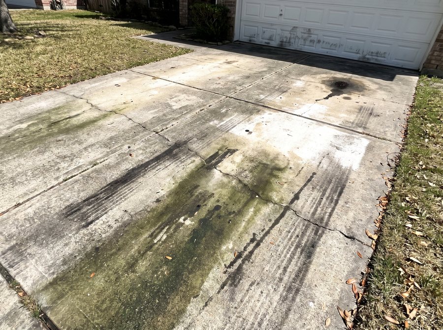 Raw phone photo of a grimy driveway, shot crooked in harsh sun.