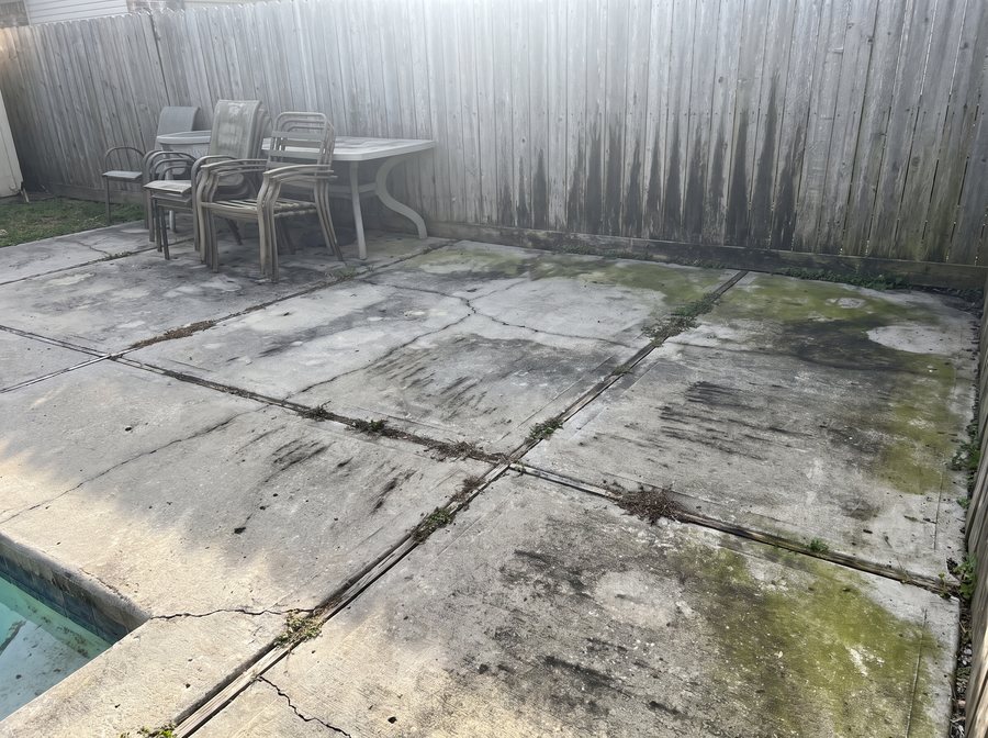 Raw phone photo of a stained pool patio and fence.