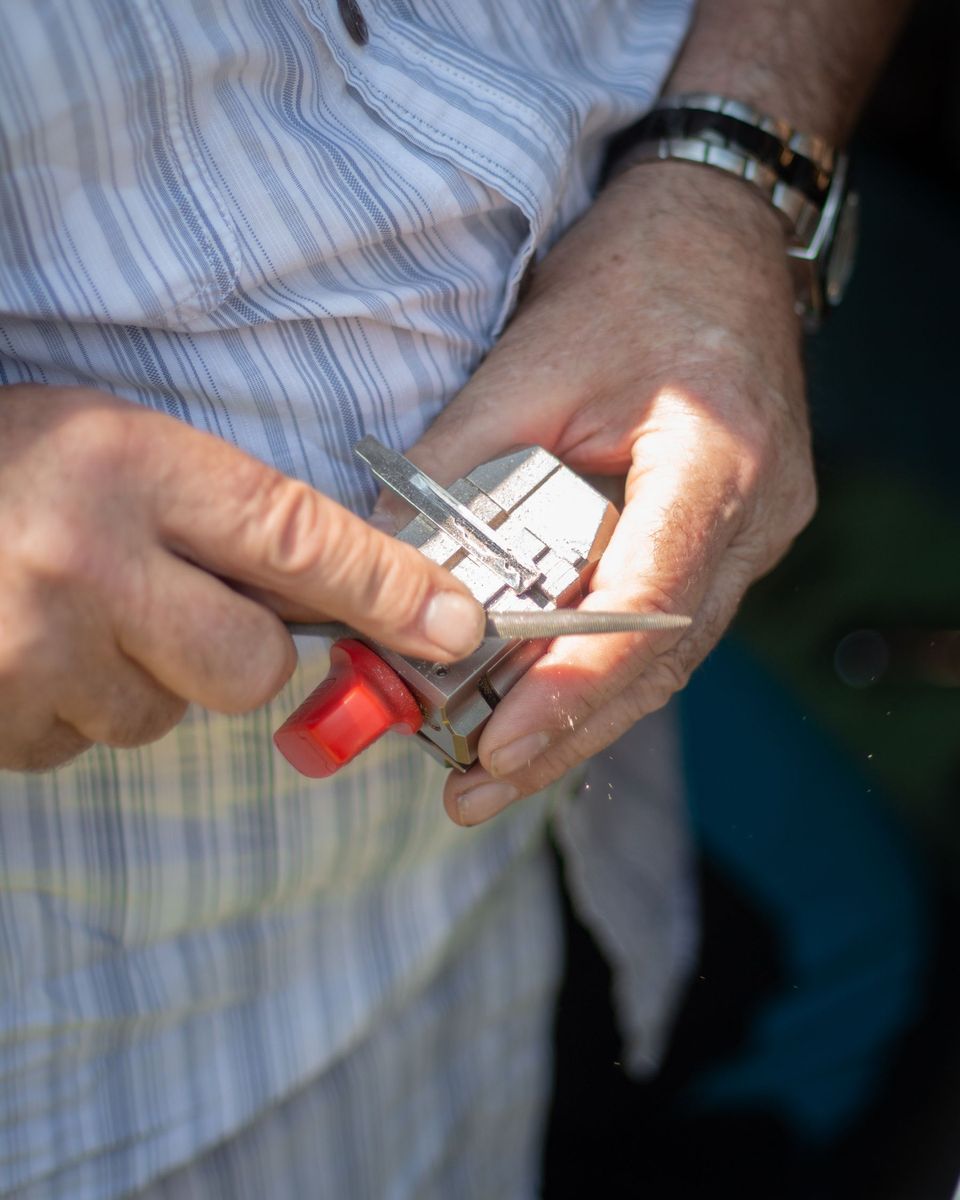 Hands filing a car key held in a small vise